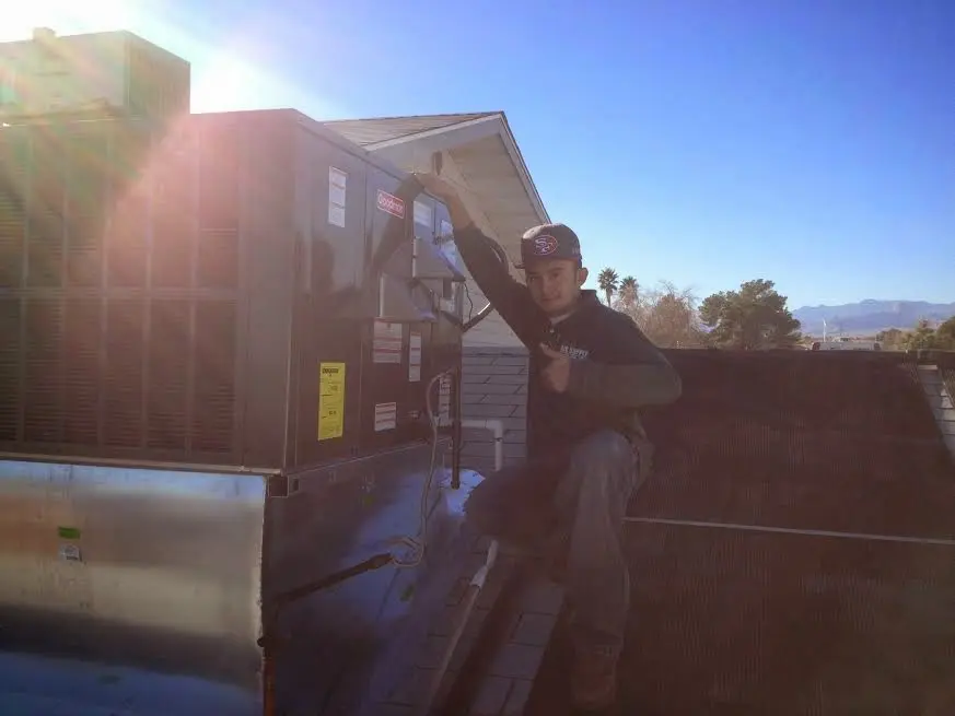 HVAC technician performing Air Duct Repair on a rooftop unit in Highland